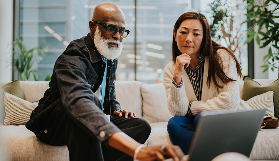 two people looking at a computer screen, representing the insights and information that AI can provide.